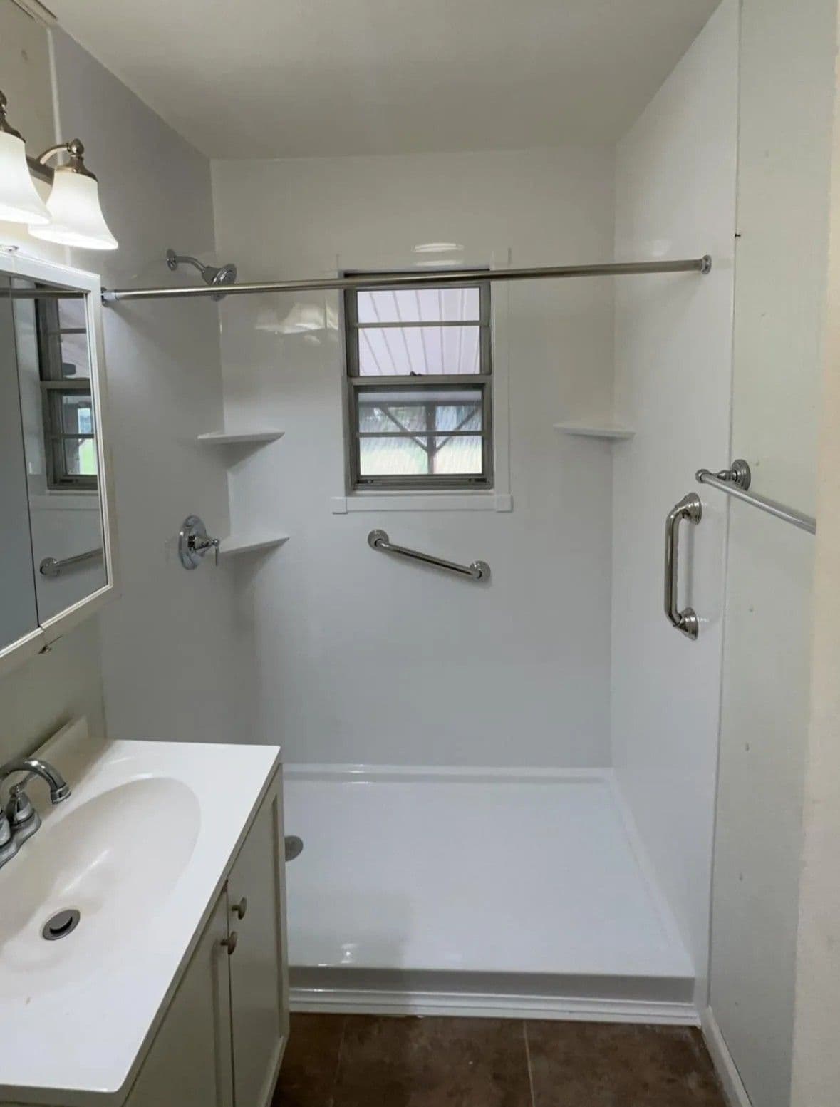 A walk-in shower with a window, corner shelves, and diagonal grab bar.